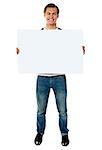 Full length view of happy smiling young man showing blank signboard