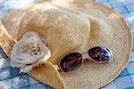 Concept of summer with straw hat and sunglasses on blue table