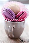 Closeup of three different flavoured macaroons in cup on wooden table