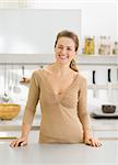 Portrait of happy young housewife in modern kitchen
