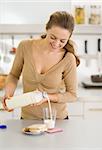 Happy young woman pouring milk into glass