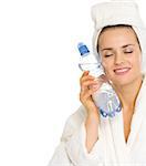 Young woman in bathrobe holding bottle with water