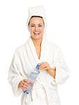 Smiling young woman in bathrobe holding bottle with water