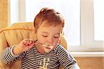 Portrait of two year old boy eating porridge in the morning.