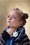 Little girl with sore throat in flu season touching her neck