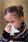 Little girl in flu season - wearing warm clothes and blowing nose