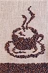 Coffee on burlap sack background forming the shape of a cup