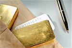 Processing and global trading of precious metals. Gold bars, certificate, pen and paper pack. Closeup.