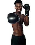 Shirtless african boxer throwing a punch at the camera