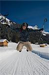 Young man jumping on a snowy trail in val di fassa, in the dolomites