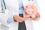 Closeup on medical doctor woman giving pills to piggy bank