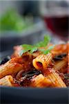 Italian food. Pasta penne with tomato sauce, olives and garnish