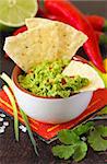 Fresh guacamole dip with nacho chips and ingredients.