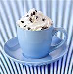 Cappuccino coffee with whipped cream in a blue cup.