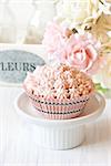 Sweet pink cupcake on a cake stand.