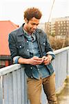 Young man texting on an iPhone in an urban setting.