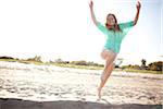 Young Woman Smiling and Jumping on Beach, Palm Beach Gardens, Palm Beach County, Florida, USA