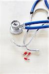 close-up of a stethoscope and pills on white background