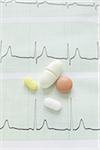 close-up of an electrocardiogram report and variety of pills