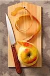 Overhead View of Apple with Skin Peeled on Cutting Board with Knife, Studio Shot