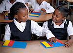 Young African schoolgirls working on abacuses inside a classroom