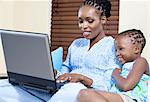 Young African girl and her mother work on a laptop computer together