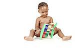 In infant sitting in front of a white background, playing with an abacus