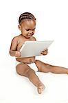 An infant sits in front of a white background, playing with a pc tablet