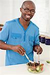 Young African man making food in a kitchen while smiling at camera