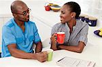 Young African married couple drinking coffee and chatting together in the kitchen