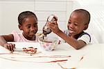 Two you African siblings make pudding together in the kitchen