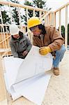 Construction supervisor reviewing home design plan with a carpenter