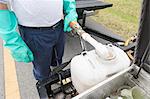 Pest control technician adding water to chemical container in truck