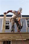 Hispanic carpenter using nail gun on home deck construction