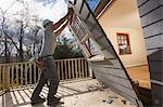 Hispanic carpenter removing newly cut door access to deck on home