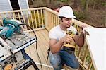 Hispanic carpenter installing hinges on new door before installation