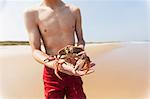 Teenage holding crab on the beach, Block Island, Rhode Island, USA