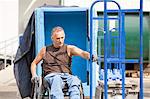 Loading dock worker with spinal cord injury in a wheelchair moving a hand truck