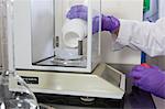 Laboratory scientist adding a solid reagent to a container on a scale