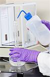 Laboratory scientist washing solid reagent into a water sample in a flask