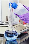 Laboratory scientist washing indigo into water sample flask