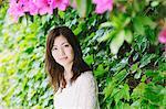 Japanese woman surrounded by green leaves looking at camera