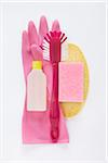 still life of cleaning products including dish scrub brush, sponges, plasic bottle, and pink rubber glove