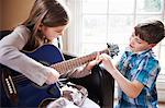 Boy helping girl play guitar