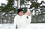 Woman taking picture in snowy forest