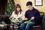 Couple eating salad on sofa