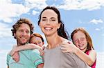 Parents carrying daughters piggyback