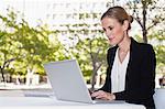 Businesswoman using laptop outdoors