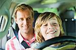 Boy driving car on fathers lap