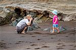 Mother taking picture of daughter on beach